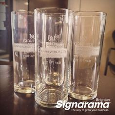 three glasses sitting on top of a table next to each other with labels on them