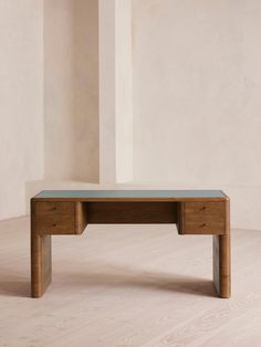 a wooden desk sitting on top of a hard wood floor next to a white wall