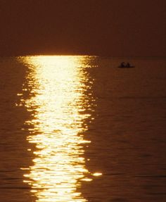 two people in a boat on the water at sunset