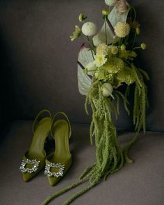 a bouquet and pair of green shoes sitting on a gray surface next to each other