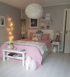 a bedroom decorated in pink and white with lights