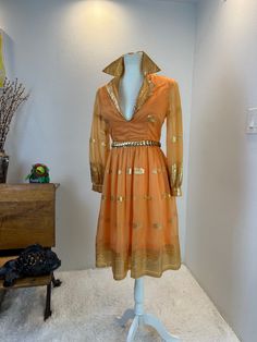 1970s / 70s dress / Vintage Oscar de La Renta dress / Oscar de La Renta dress gold dress / 1970s fashion   This late 1960s, early 1970s Oscar Della Renta dress is stunning. She is orange with the most vibrant gold print I have ever seen. Cleary high quality fabric as the gold hasn't faded a single bit in over 50 years. Oscar wanted you to wear the collar up, as evident by the hooks at the back of the neck. I also photographed it with the neck down in case you prefer it that way.  She has the sheer outter layer and a soft orange lining. She has deep plunge neckline that was clearly made to show cleavage. But really it's the gold print that gets me every time! Just watch the video and see! Measurements provided are flat and have been doubled.  Bust 36 Waist 26"  Hips 42"   Length 38" shoulde Gold Dress For Spring Costume Party, Gold Costume Party Dress For Spring, Gold Dresses For Spring Costume Party, Gold Cocktail Dress For Fall, Retro Vintage Long Sleeve Dress For Party, Retro Long Sleeve Vintage Dress For Party, 1970s Style Evening Dresses For Fall, Mid-century Vintage Dress For Party, 70s Inspired Long Sleeve Party Dresses