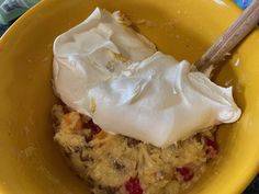 a yellow bowl filled with some type of dessert and whipped cream on top of it