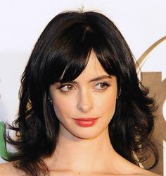 a close up of a person with dark hair and wearing a strapless dress at an event