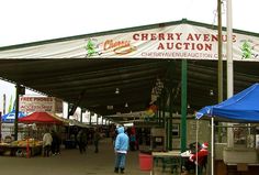 an outdoor market with tents and people shopping under the awning for cherry avenue auction