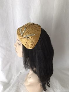 This vintage inspired gold pleated silk dupioni half hat fascinator with gold and silk rhinestone trim. This gold headpiece is perfect to wear as a bridal Juliet Cap, women's formal church hat, derby style tea parties, mother of the bride hat, wedding guest hat or any other special occasion. Please note this is handmade by order and so the pleating maybe slightly different from the one shown. We pride ourselves on making sure you receive a beautifully designed headpiece that's truly yours. Easy Elegant Gold Costume Hats And Headpieces For Ceremonial, Gold Gatsby Style Formal Headpieces, Vintage Gold Headpiece For Evening, Elegant Ceremonial Headpiece With Pinched Crown, Gold Gatsby Headpiece For Vintage Events, Gold Gatsby Headpieces For Evening, Gold Gatsby Evening Headpieces, Elegant Gold Headpieces For Ceremony, Vintage Gold Headband For Party