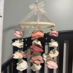 a crib mobile with pink and white flowers hanging from it's sides in a nursery