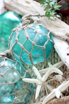 some blue glass balls in a basket with starfish and seaweed on the beach