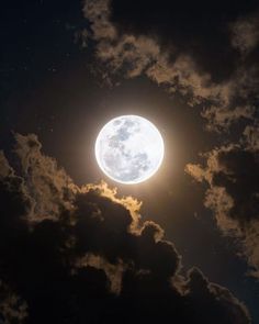 the full moon is shining brightly in the night sky with fluffy clouds and dark blue skies