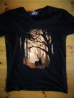 a black t - shirt with an image of a deer in the woods on it