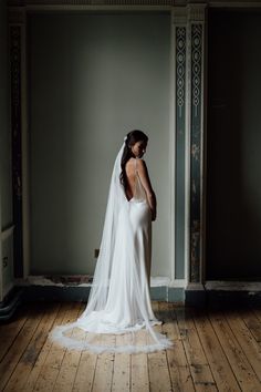 a woman in a wedding dress standing on a wooden floor with her back to the camera