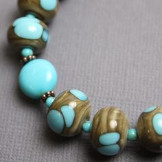 "This one of a kind turquoise and lampwork bead bracelet is eye catching and beautiful. This bracelet features all natural Kingsman Turquoise beads strung along side my handmade lampwork glass beads. The beads are a shade of greenish brown with pops of turquoise blue. I have made the lampwork beads in this bracelet. The strand is joined with a simple chocolate gold plated clasp. There is a length of chain at the end with a little bead charm that makes this bracelet adjustable in length. Length: Blue Bracelets With Unique Round Beads, Handmade Round Turquoise Bracelets, Artisan Turquoise Round Bracelet, Bohemian Turquoise Glass Bracelets, Turquoise Czech Glass Bead Jewelry, Unique Turquoise Czech Glass Beaded Bracelets, Turquoise Czech Glass Round Beads Jewelry, Handmade Turquoise Round Beaded Bracelets, Handmade Round Turquoise Beaded Bracelets