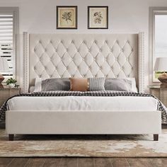 a white bed sitting in a bedroom on top of a hard wood floor next to two windows