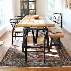 a dining room table with four chairs and a rug on the floor in front of it