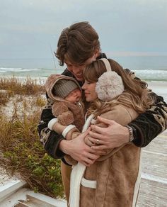 a man and woman hug each other while standing on a boardwalk next to the beach