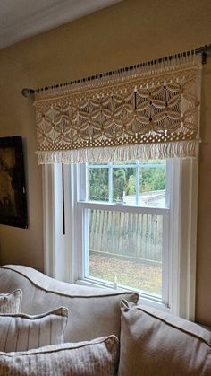 a living room with a white couch and two pillows on top of it, next to a window