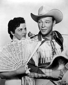 a man in a cowboy hat holding a fan next to a woman