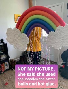 a man holding up a rainbow shaped balloon in his room with the caption not my picture she said she used pool noodles and cotton balls and hot glue