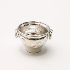 a silver bowl with two handles on a white surface