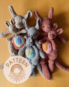 three crocheted stuffed animals sitting next to each other on a yellow surface with the word pattern written below them