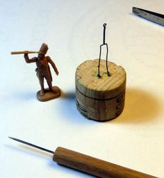 a toy figurine holding a stick next to a wooden box with two small figures on it