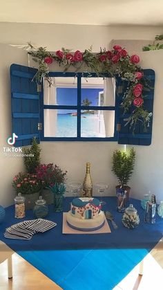 a blue table topped with a cake and flowers