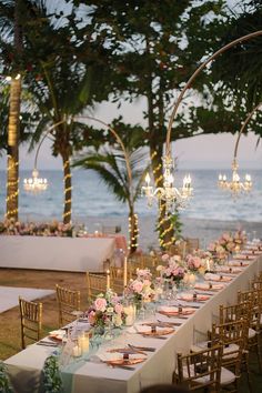 a long table is set up with flowers and candles for an outdoor dinner by the ocean