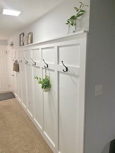 an entry way with white cabinets and plants on hooks hanging from the wall, along with carpeted flooring