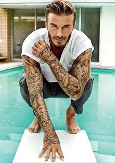 a man with tattoos on his arms leaning over a pool