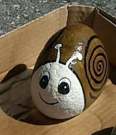 a painted snail sitting in a cardboard box