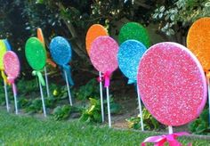 colorful candy lollipops are lined up in the grass with ribbons on them