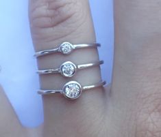 three diamond rings sitting on top of each other in front of a person's hand