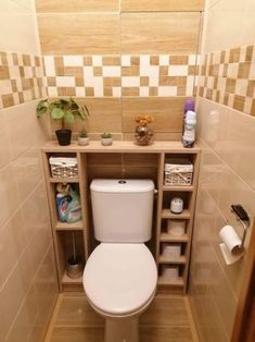 a white toilet sitting inside of a bathroom next to a wooden shelf filled with items