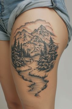 a woman's thigh with a mountain scene tattoo on it