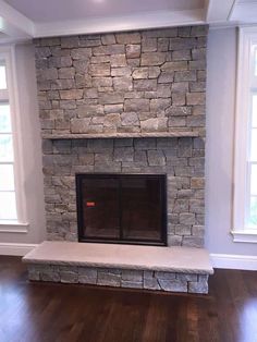 an empty room with a stone fireplace and hardwood floors