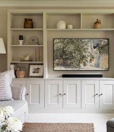 a living room filled with furniture and a flat screen tv on top of a wooden shelf