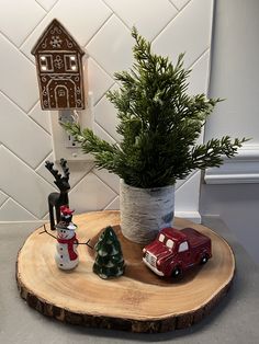 a small christmas tree in a pot on top of a wooden table with toy cars