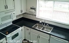 a kitchen with white cabinets and black counter tops, including a stove top oven next to a sink