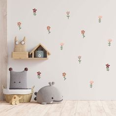 two stuffed animals sitting next to each other in front of a wall with flowers on it