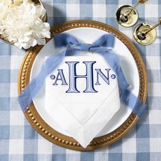 a blue and white table cloth with the letters ahn on it is sitting on a gold plate