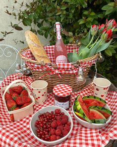 a picnic table with strawberries, watermelon, cucumbers and bread