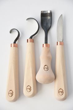 three wooden utensils and two metal spoons on a white surface with a black handle