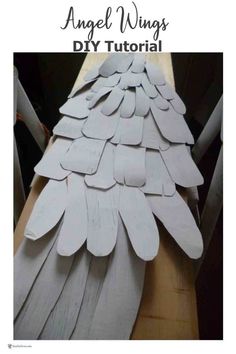 an angel wing made out of white paper on top of a wooden table with text overlay