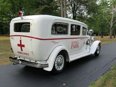 an old ambulance is parked on the side of the road in front of some trees