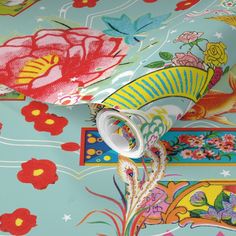 an artistically designed table cloth with colorful flowers and birds on it, along with other decorative items