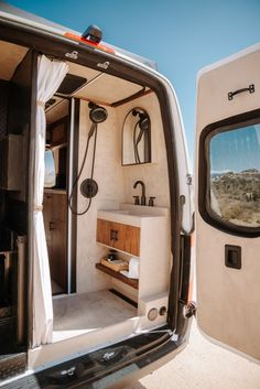 the interior of a camper van with its door open to reveal a sink and shower