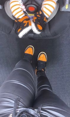 the legs and feet of a person in black pants, wearing orange striped socks while sitting in a car seat