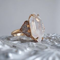 a close up of a ring on top of a silver cloth with white and brown stones