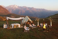 a tent set up in the middle of a field with chairs around it and a fire pit