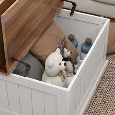 an open storage box with stuffed animals and bottles in it on carpeted floor next to couch